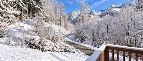 A snow-covered landscape with a wooden deck and a mountain view.