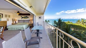 Un balcon aménagé avec un lit, des chaises et une table, offrant une vue sur l’océan.