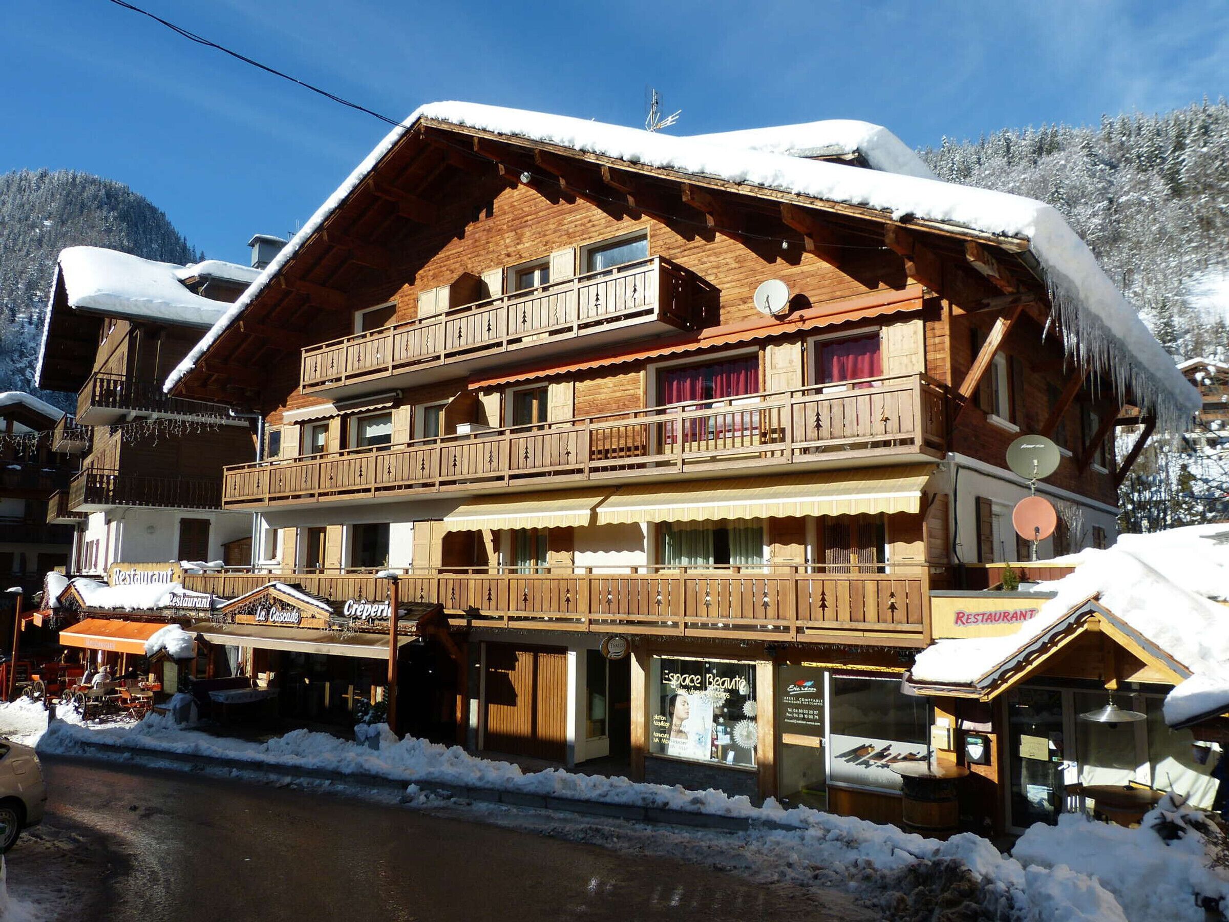 A multi-story wooden building with balconies, a restaurant, and a shop.