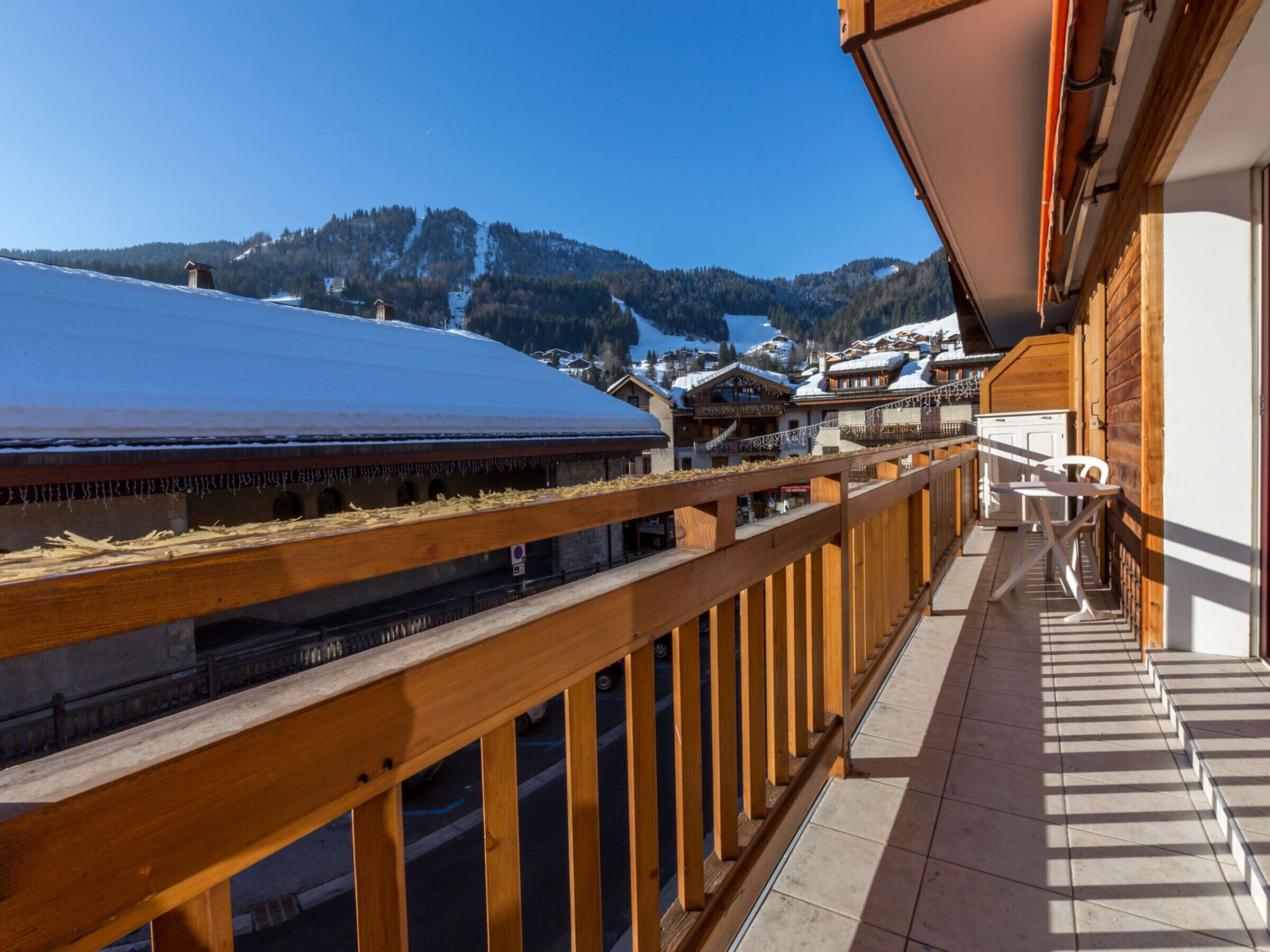 A balcony with a wooden railing overlooking a snowy mountain landscape.