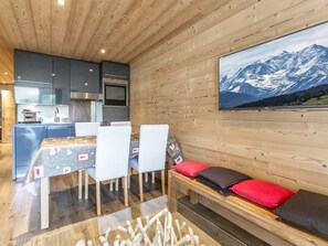 A modern kitchen with built-in appliances, a dining area with a table and chairs, and a large window with a mountain view.