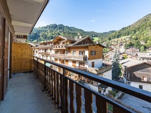 Un balcon offrant une vue sur un village de montagne, des bâtiments en bois et un ciel dégagé.