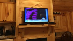 Un téléviseur fixé au mur en bois d’une pièce aménagée dans le style d’un chalet.