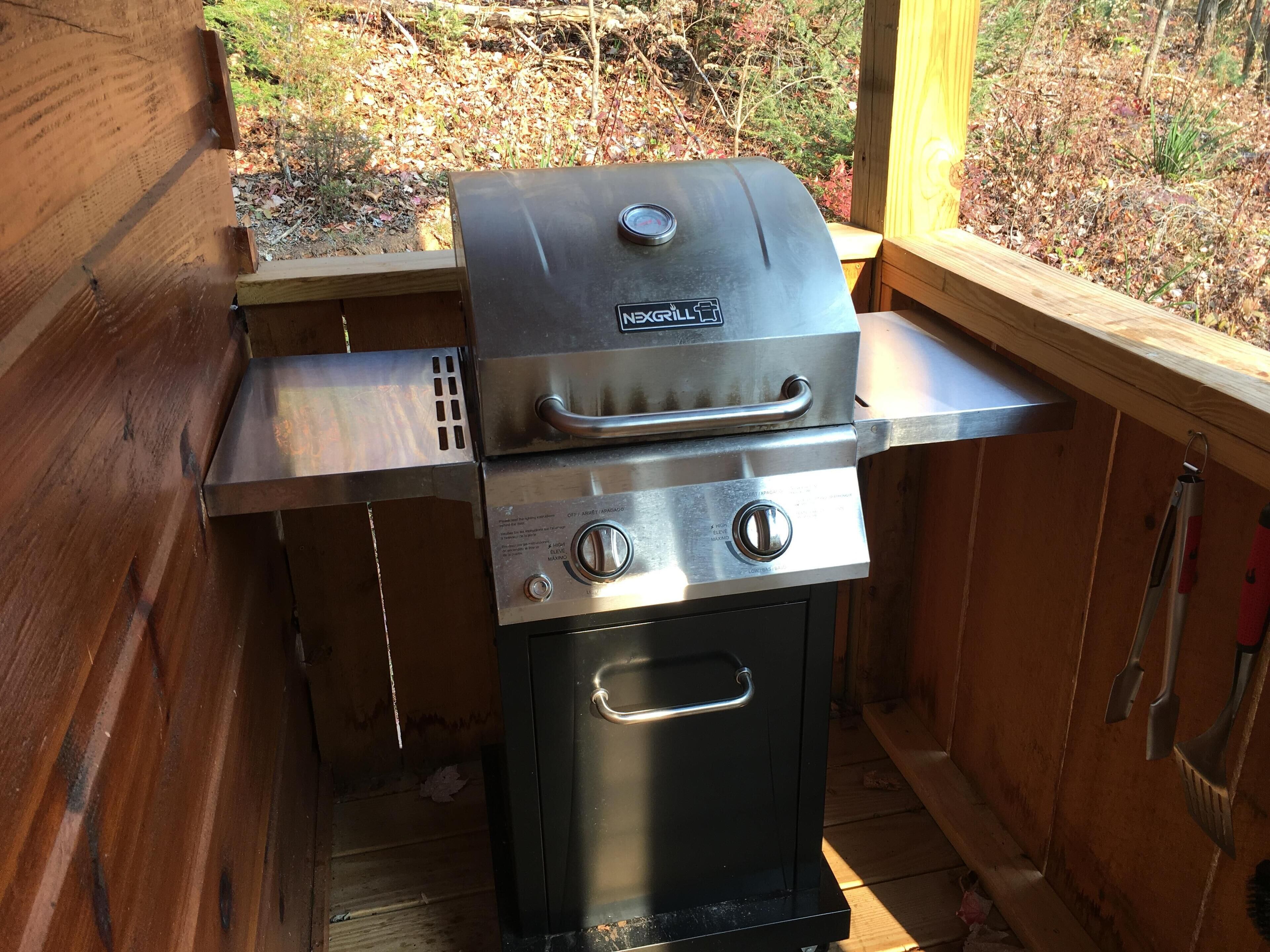 A compact outdoor grill with a digital thermometer, a side shelf, and a stainless steel finish.