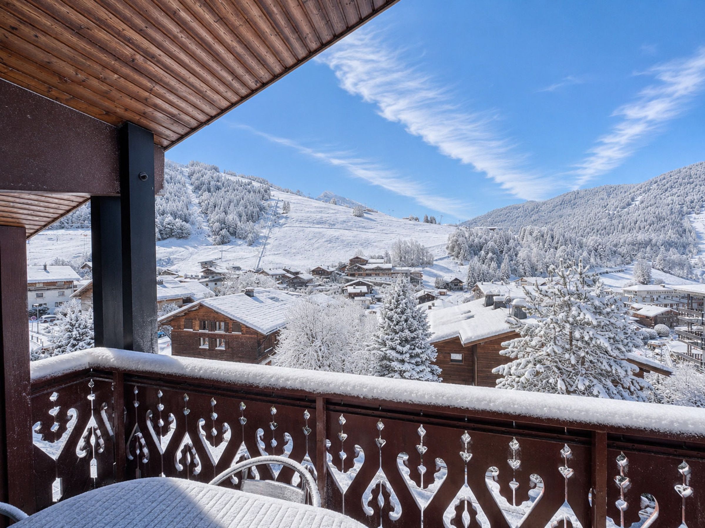 A balcony with a view of a snow-covered village and mountains.