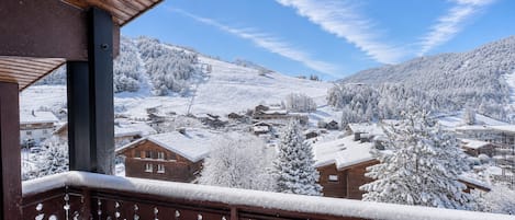 A balcony with a view of a snow-covered village and mountains.