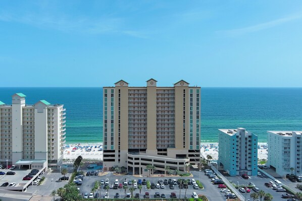 A high-rise hotel with a parking lot and a beach view. - NEWLY UPDATED FURNITURE! | Outdoor Pool | Hot Tub | Sauna | BEACHBALL PROPERTIES (Gulf Shores)