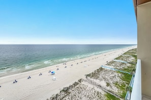 A beach with a clear view of the ocean, a sandy shoreline, and a few beach umbrellas.