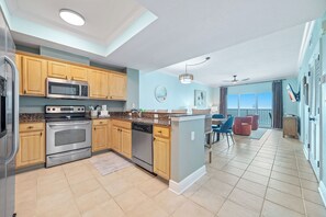 A modern kitchen with built-in appliances, wooden cabinets, and a dining area with a view.