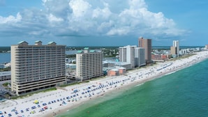 A coastal cityscape with a beachfront hotel, high-rise buildings, and a crowded beach. - NEWLY UPDATED FURNITURE! | Outdoor Pool | Hot Tub | Sauna | BEACHBALL PROPERTIES (Gulf Shores)