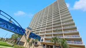 Un hotel alto con múltiples balcones y una estructura de puente azul al frente.