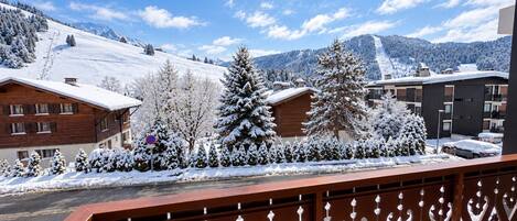 A snow-covered mountain landscape with buildings and a wooden fence.