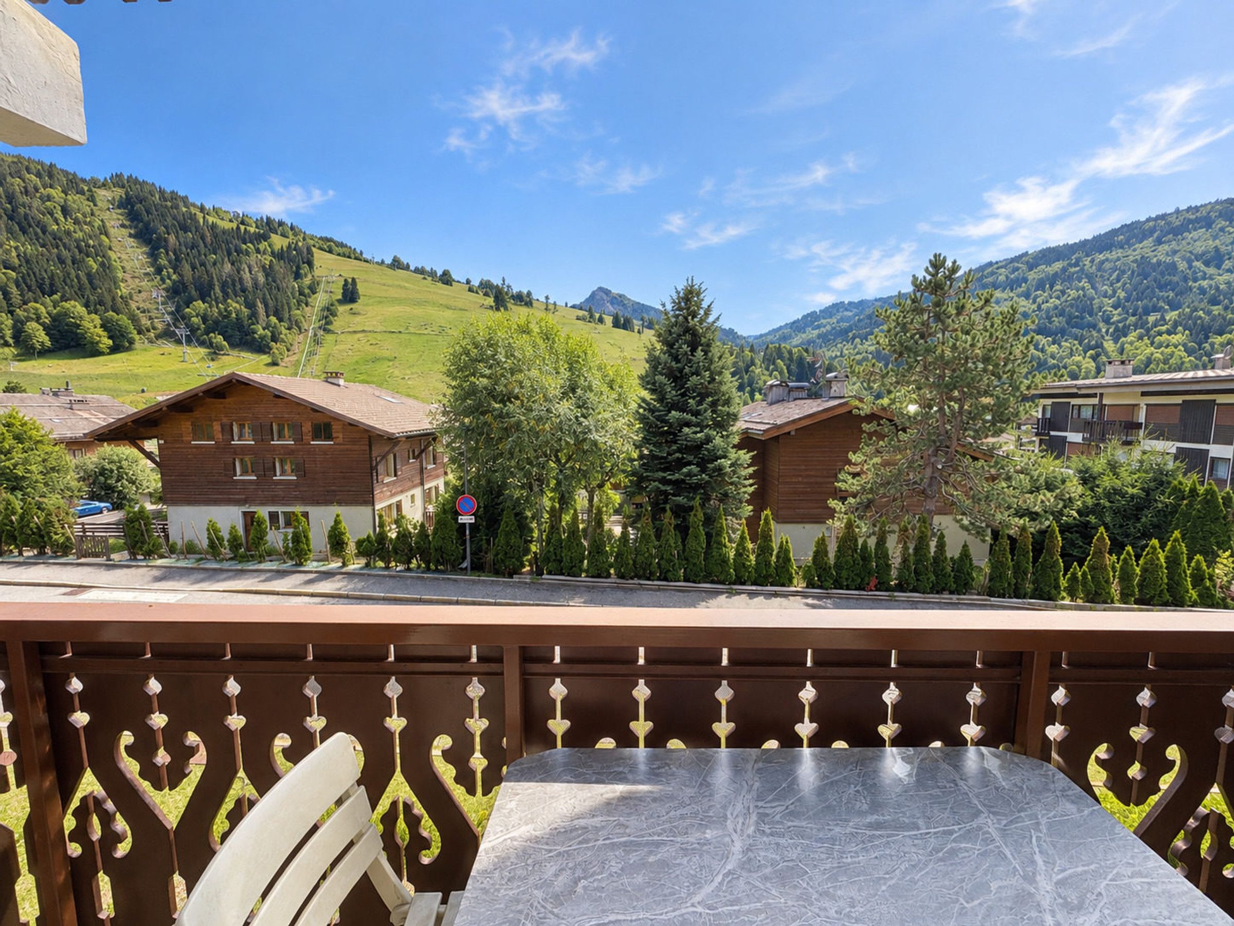 A terrace with a view of a mountain landscape, wooden buildings, and a no parking sign.