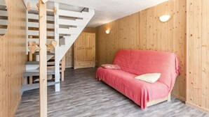 Ett mysigt rum med en trätrappa, en röd soffa och en trägarderob.