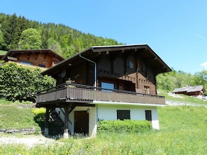 A wooden chalet with a balcony, a staircase leading to the entrance, and a mountainous backdrop. - Chalet for 10 people, near slopes, with fireplace and garage, pets allowed (La Clusaz)