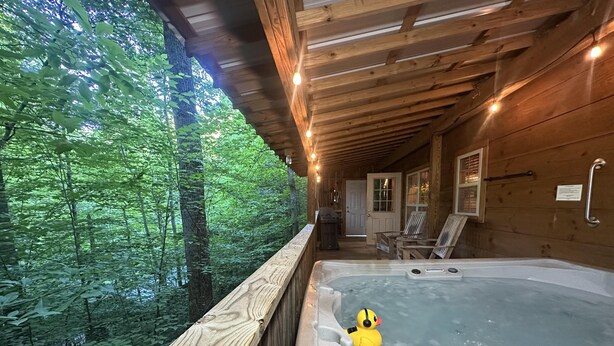 A wooden cabin with a hot tub and a duck float, surrounded by a forest. - “Lovey Dovey: Your Romantic Asheville Cabin Escape” (Asheville)