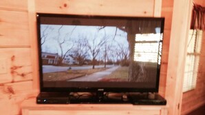 A television mounted on a wooden wall above a fireplace with a stone surround.