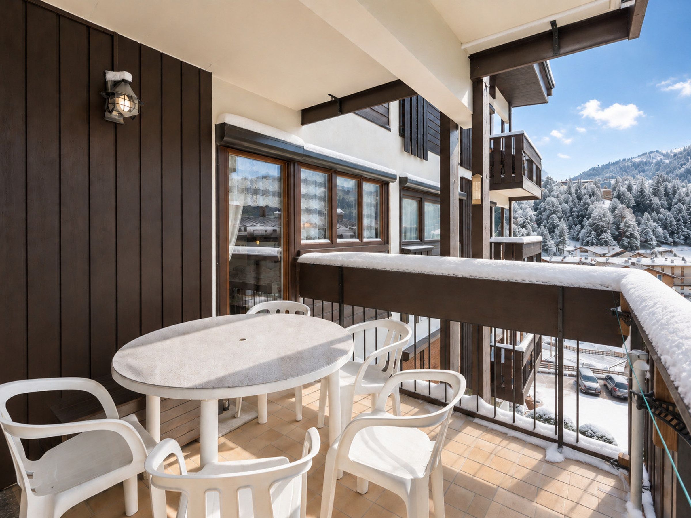Un balcon avec une table ronde et quatre chaises, donnant sur un paysage enneigé.