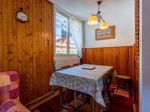 Ein Zimmer mit Holzwänden, einem Tisch mit gemustertem Tuch, einer Uhr und einem gerahmten Bild an der Wand.