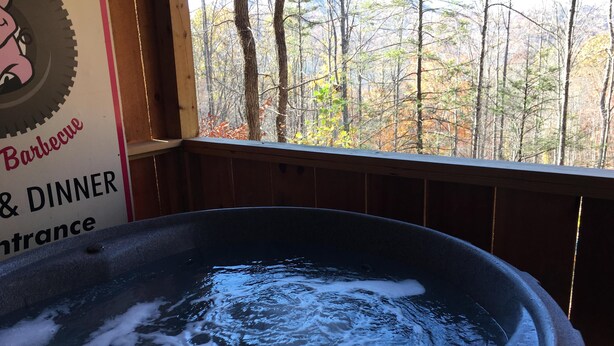 Un jacuzzi con agua, rodeado por una terraza de madera y vistas a árboles.