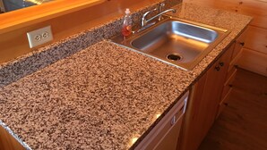 Una cocina con encimeras de granito, un lavamanos de acero inoxidable, armarios de madera y un horno empotrado.