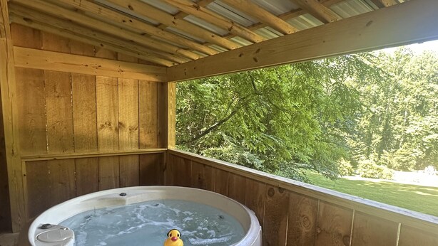 Eine Holzhütte mit Whirlpool und einer Quietscheente.