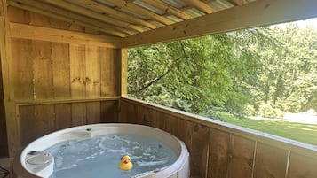Una cabana de fusta amb un banyera hidromassatge que conté un ànec de goma.