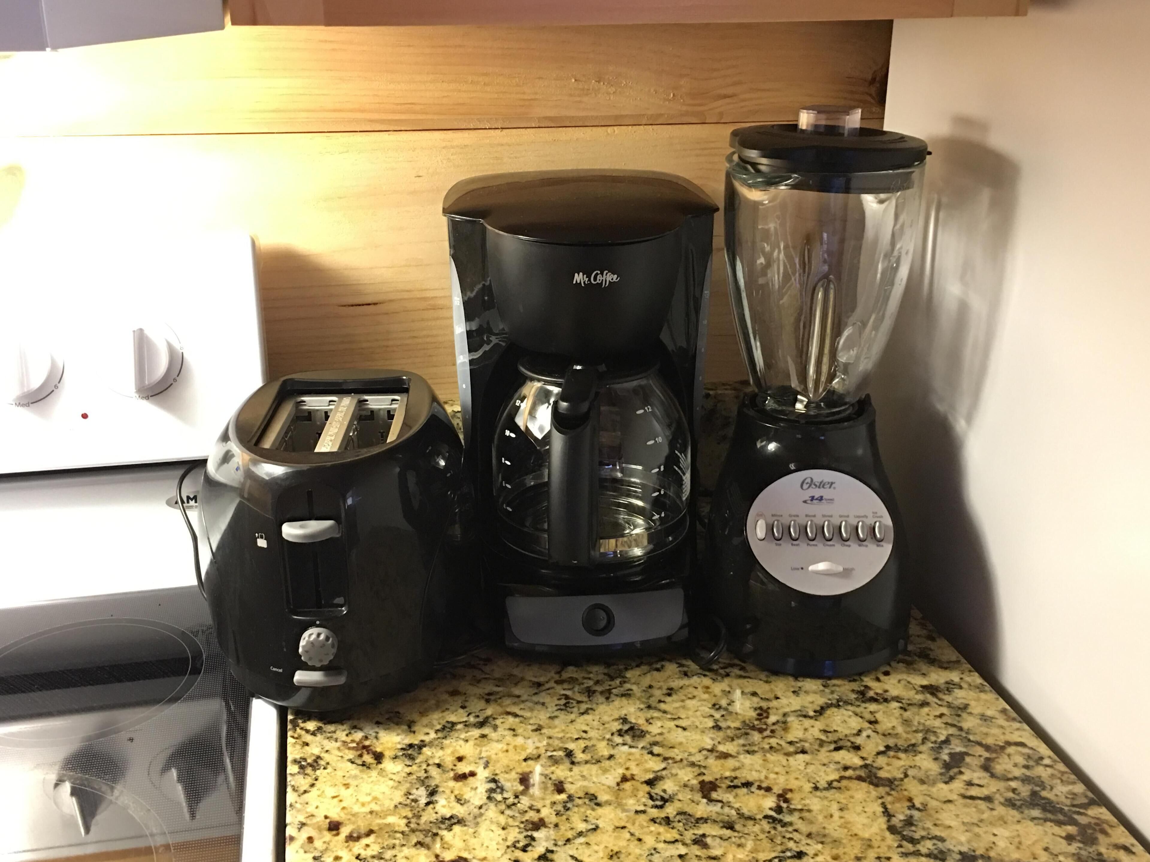 Un plan de travail de cuisine avec un grille-pain, une machine à café et un mixeur.