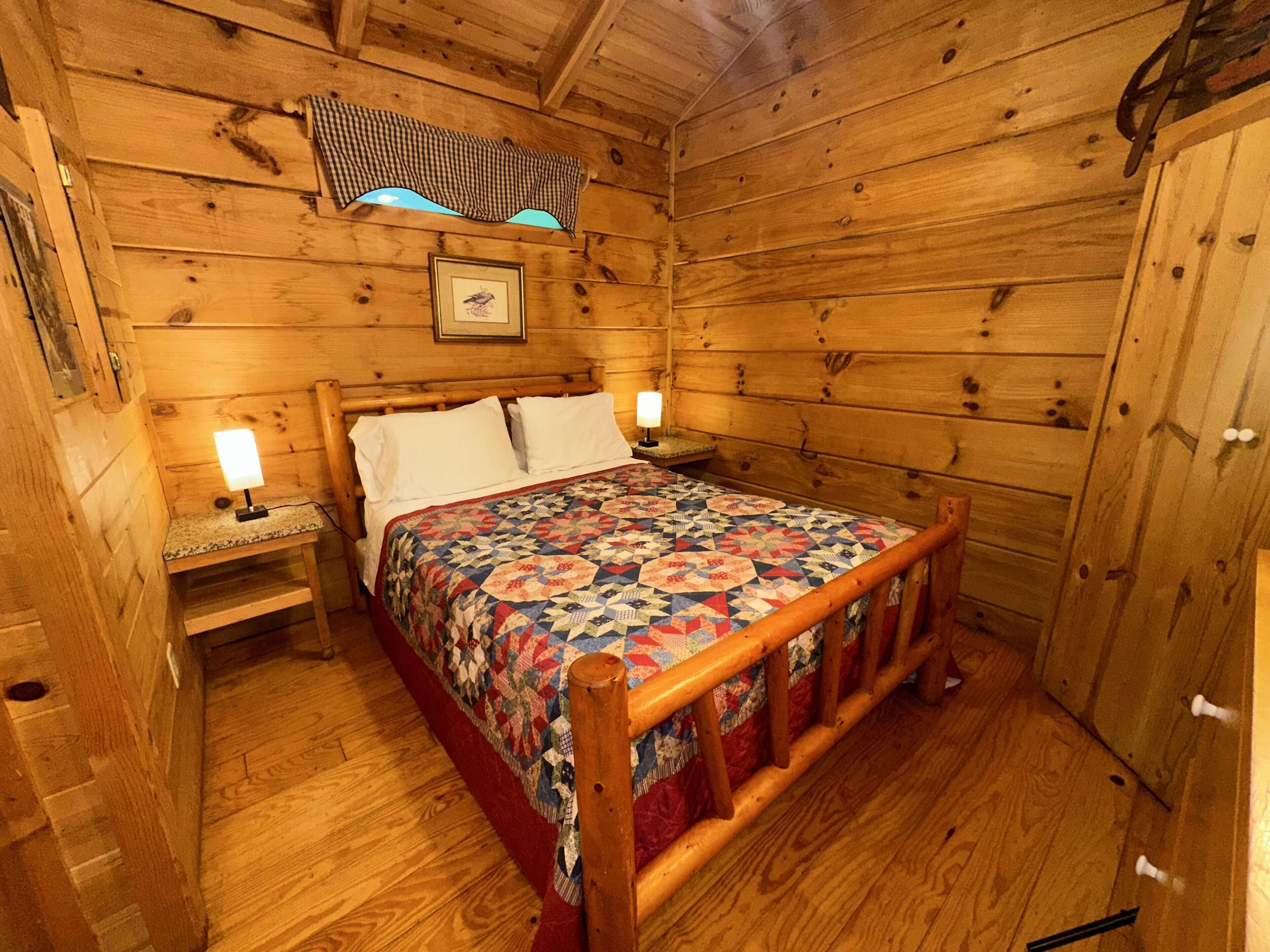 A wooden cabin bedroom with a bed, nightstands, and a quilt.