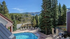 Un área de piscina con jacuzzi, sillones de descanso y vistas a las montañas.