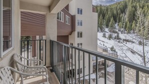 Un balcón con vistas a una montaña nevada y un edificio con múltiples ventanas.