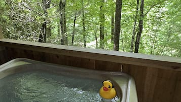 A wooden deck with a hot tub and a rubber duck.