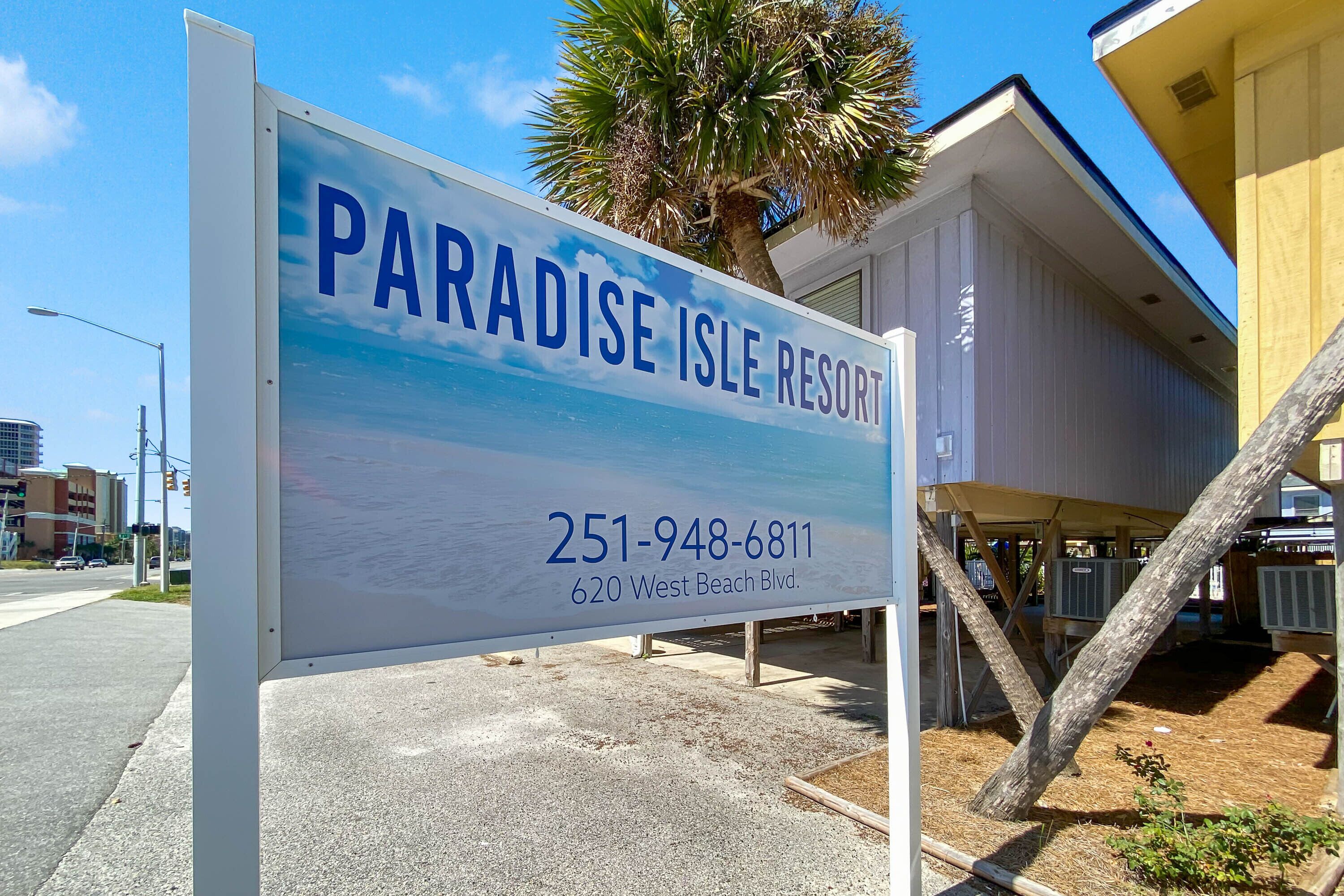 Un panneau indiquant le Paradise Isle Resort, avec le numéro de téléphone et l’adresse.