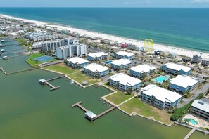 An aerial view of a coastal hotel area with buildings, a beach, and a marina.