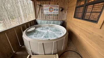 A wooden cabin with a hot tub, a sign reading "Veterans of Foreign Wars Post No 891", and a window with blinds.