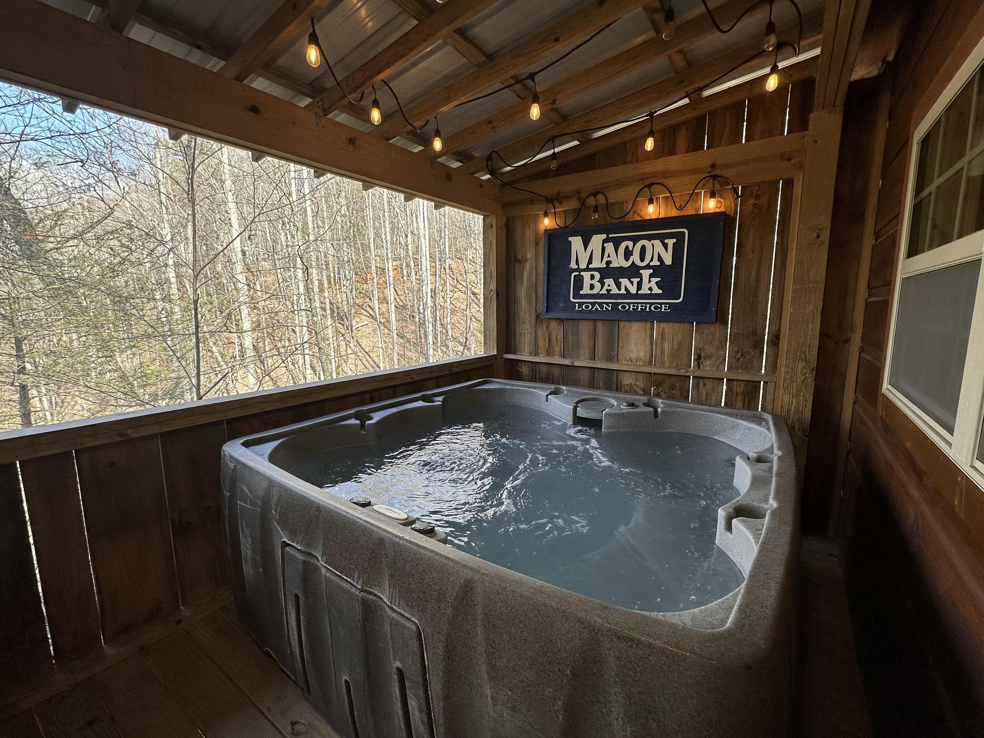 A wooden cabin with a hot tub and a sign for 'Macon Bank Loan Office'.