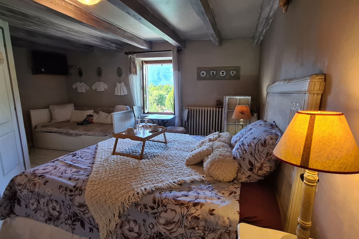 A bedroom with a bed, a bedside table, a lamp, a window, and a radiator.