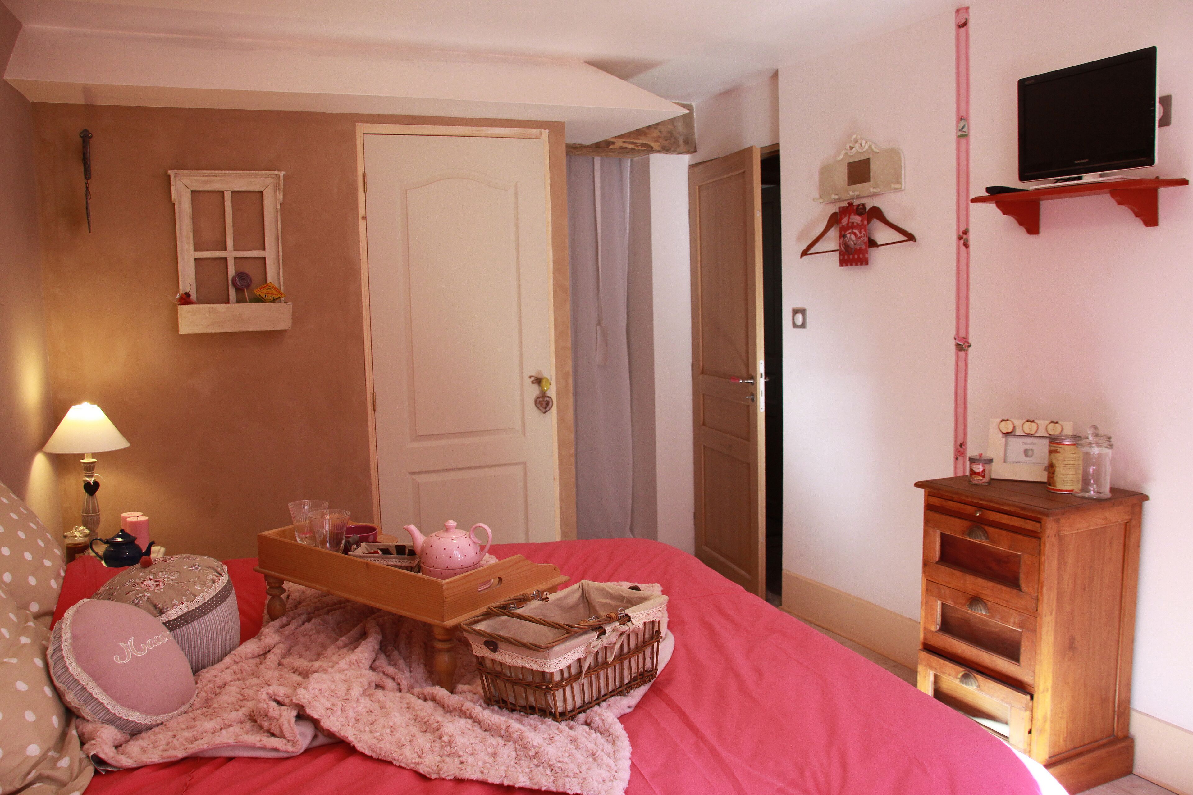 Een slaapkamer met een bed, nachtkastje, kaptafel en een televisie op een plank.
