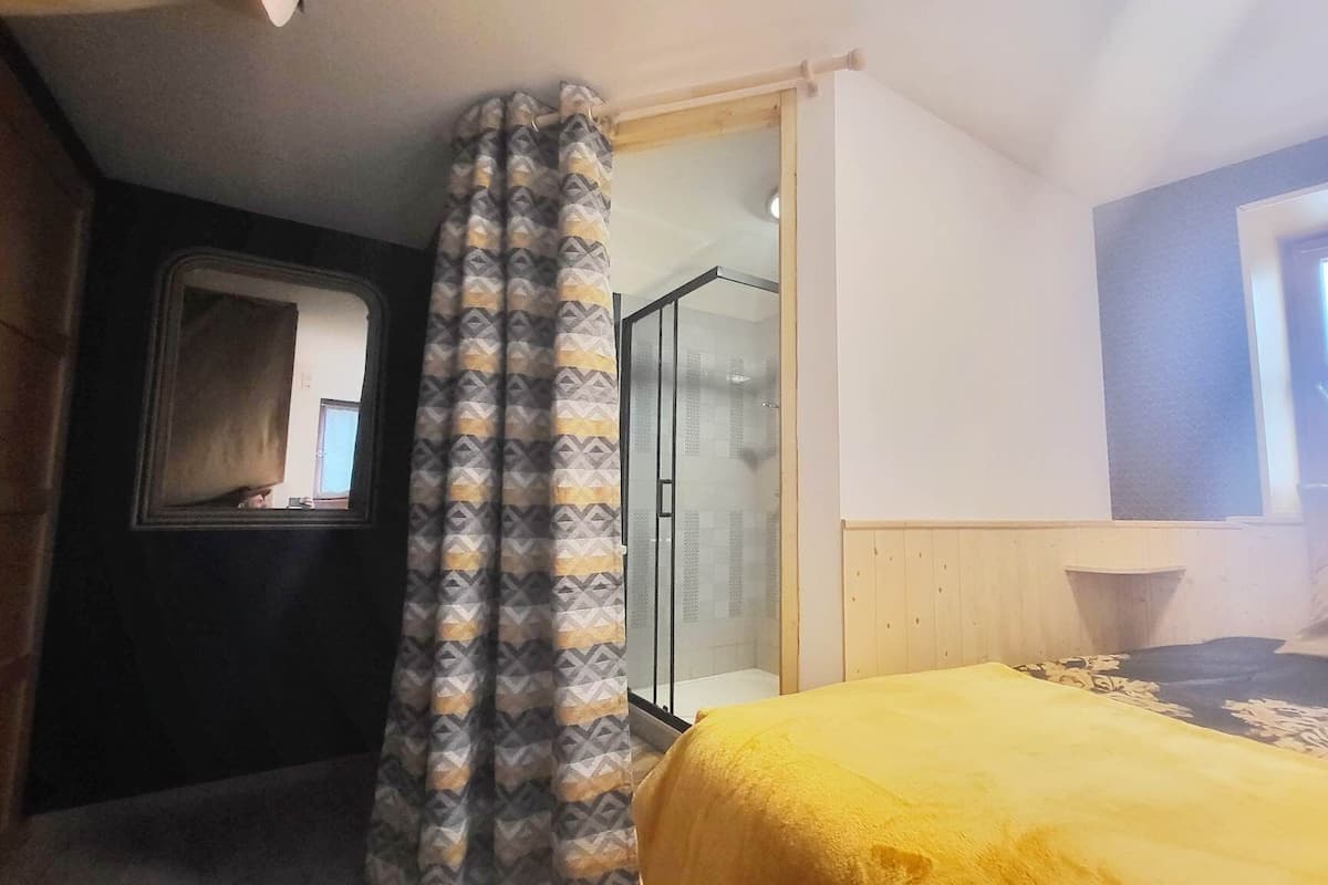 A bedroom with a bed, a shower, and a window.