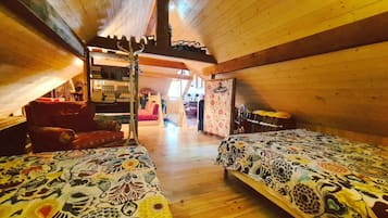 Una camera da letto mansardata accogliente con due letti, un soffitto in legno e una scala che conduce a un livello superiore.