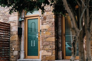 A stone building with a green door and a wooden door, both with glass panels and a small sign above the green door. - Chios City Inn (Chios)