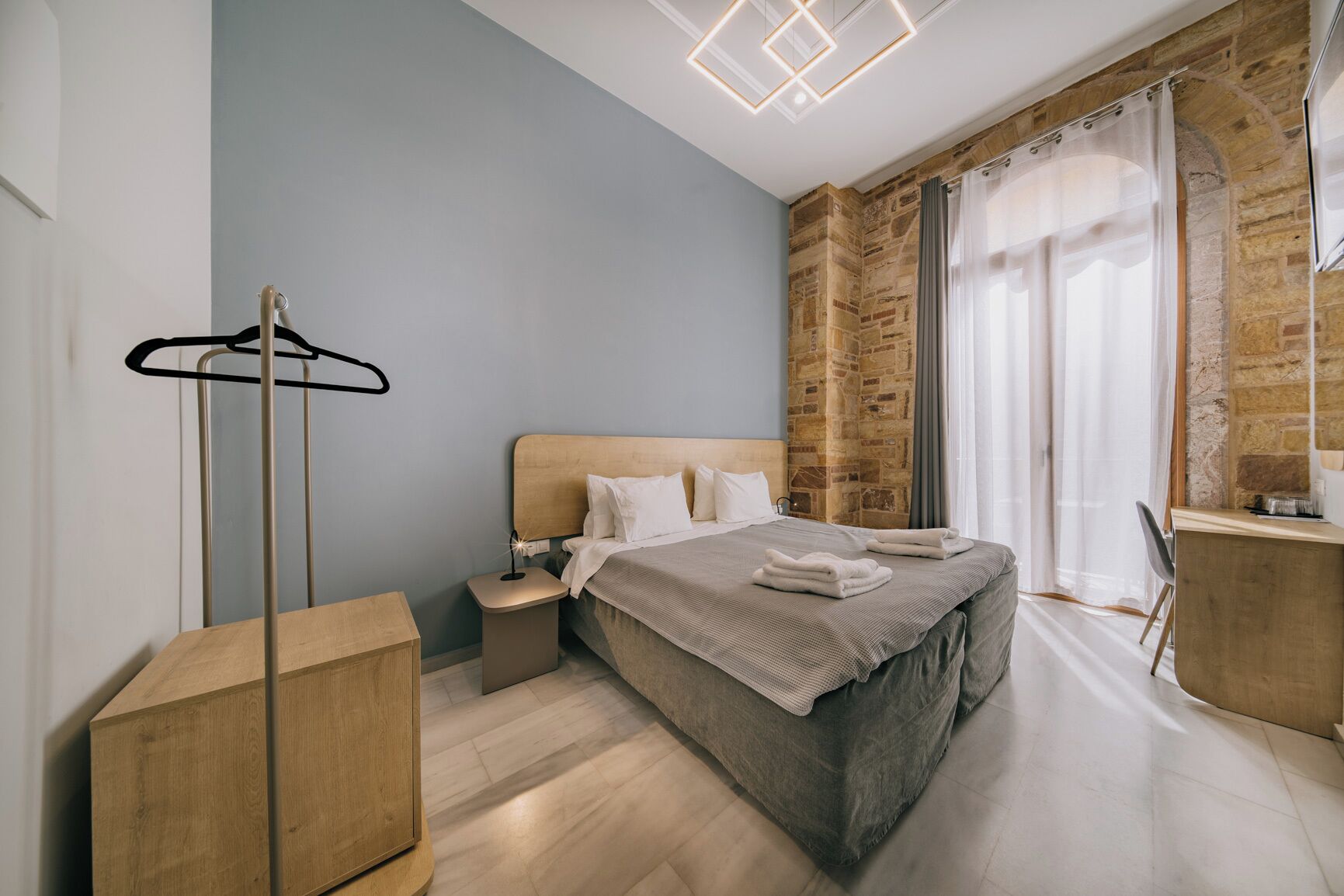 A modern bedroom with a bed, bedside table, and a coat rack.