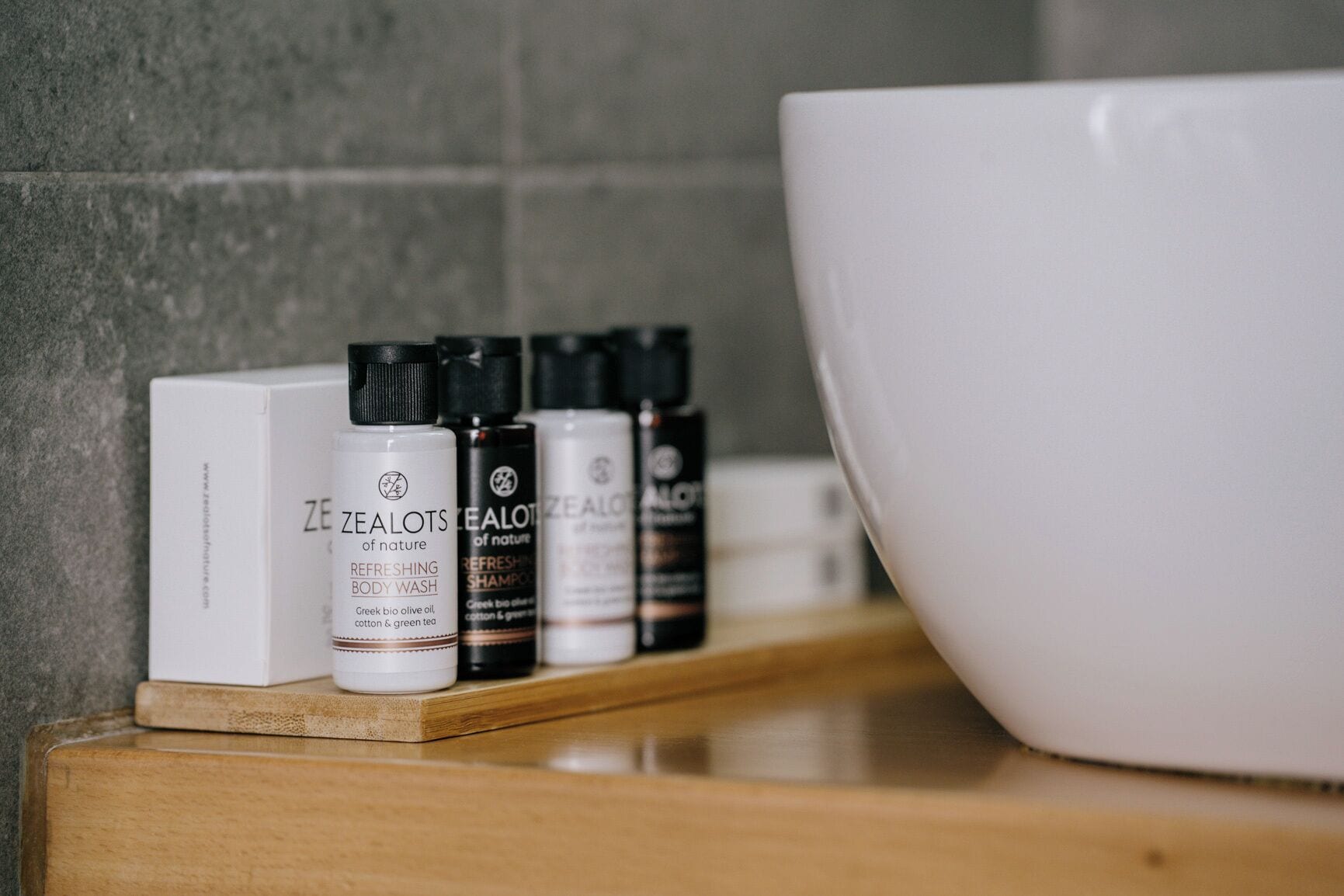 Ein Badezimmerschrank mit Flaschen von ZEALOTS Duschgel und Shampoo sowie eine große weiße Waschtasche.