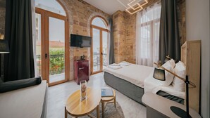 Una habitación de hotel moderna con una cama grande, un escritorio pequeño, un televisor y un balcón con vistas.