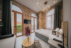 Una habitación de hotel moderna con una cama grande, un escritorio pequeño, un televisor y un balcón con vistas.