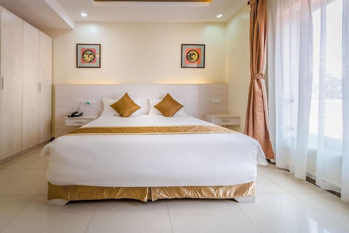 A large bed with a gold accent, two bedside tables, a nightstand, and a headboard.