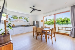 Una cocina moderna con comedor, ventanas amplias y ventilador de techo.
