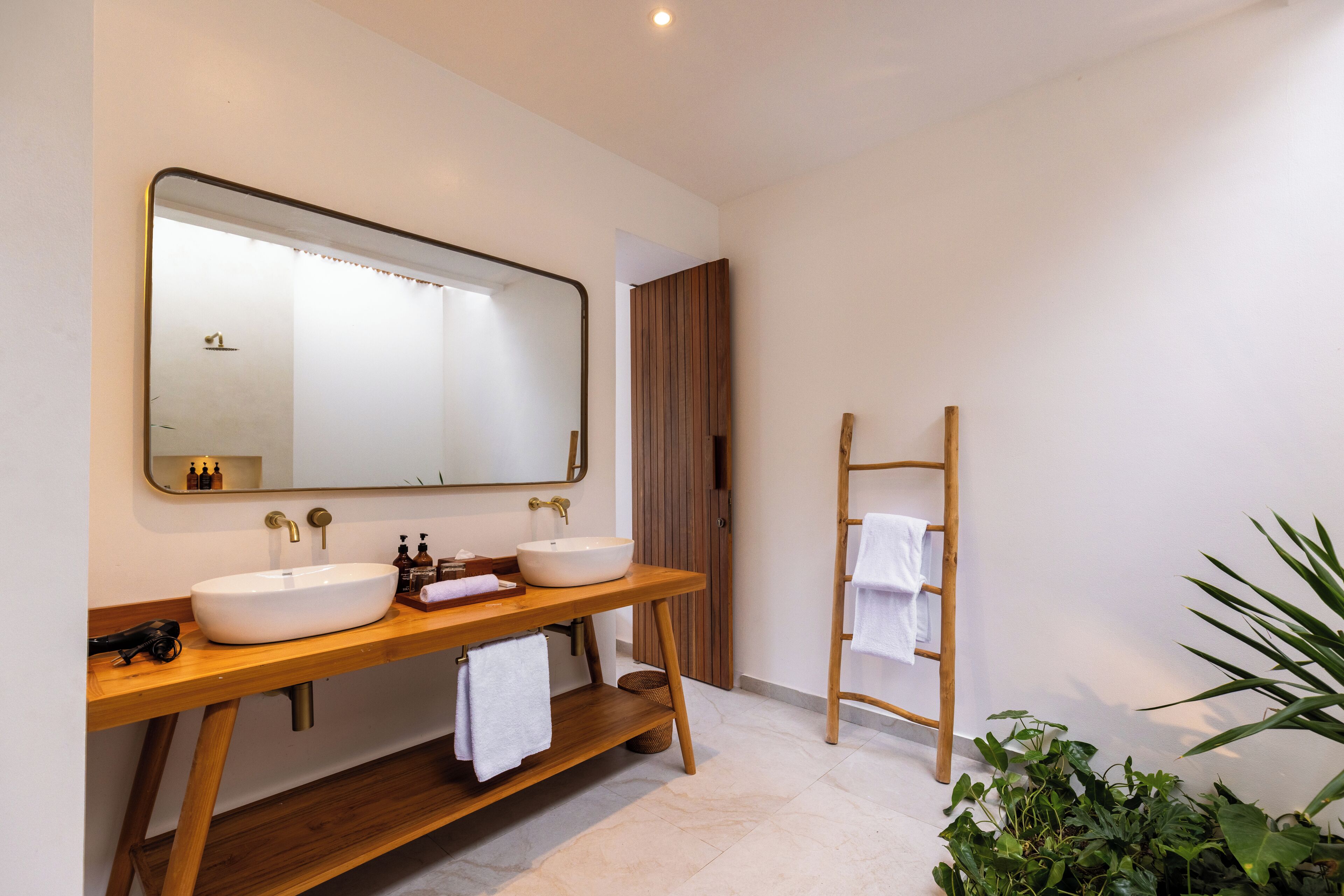 A modern bathroom with two sinks, a large mirror, and a wooden vanity.