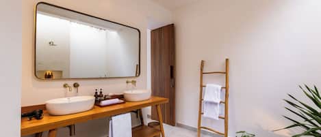A modern bathroom with two sinks, a large mirror, and a wooden vanity.