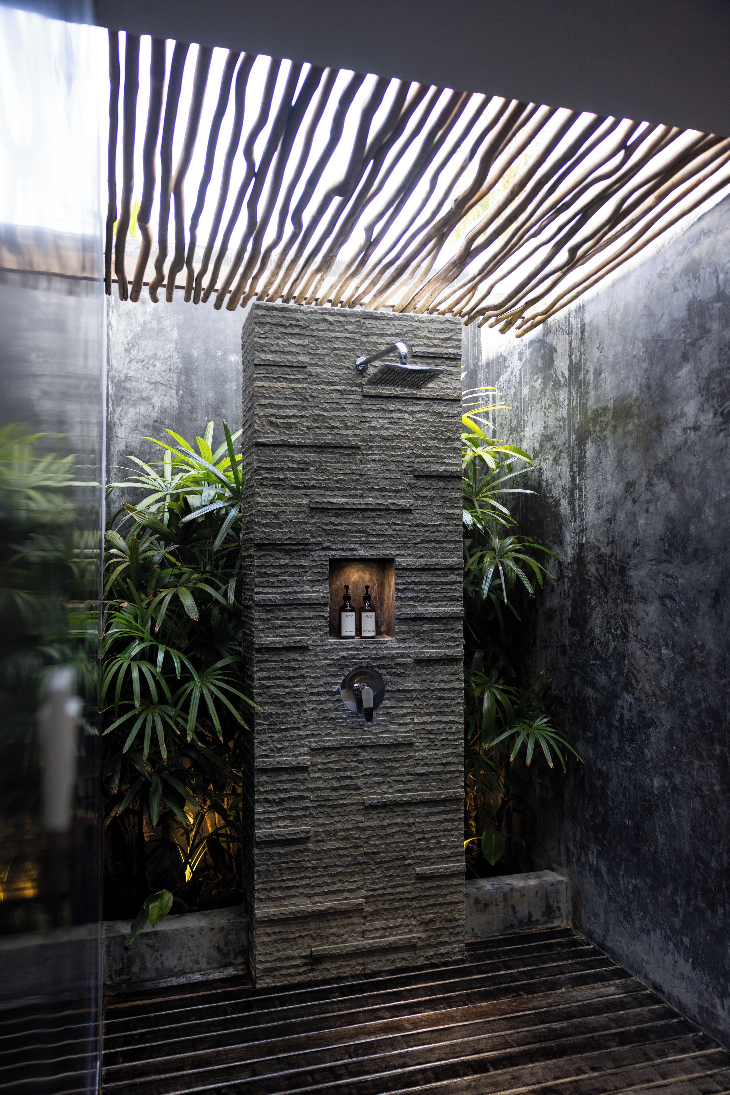 A modern bathroom with a stone wall, a wooden door, and a glass enclosure.